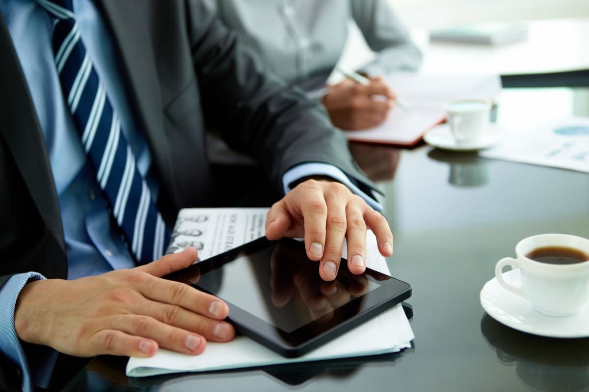 homme daffaires dans son lieu de travail avec un journal une tasse de cafe et une tablette